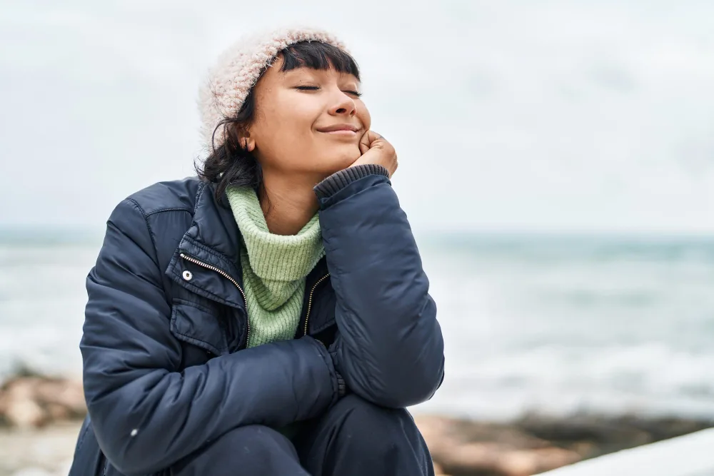 Woman reflecting quietly near the water during a period of low mood and emotional fatigue