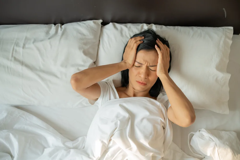 Woman remaining awake in bed while struggling to settle into restorative sleep